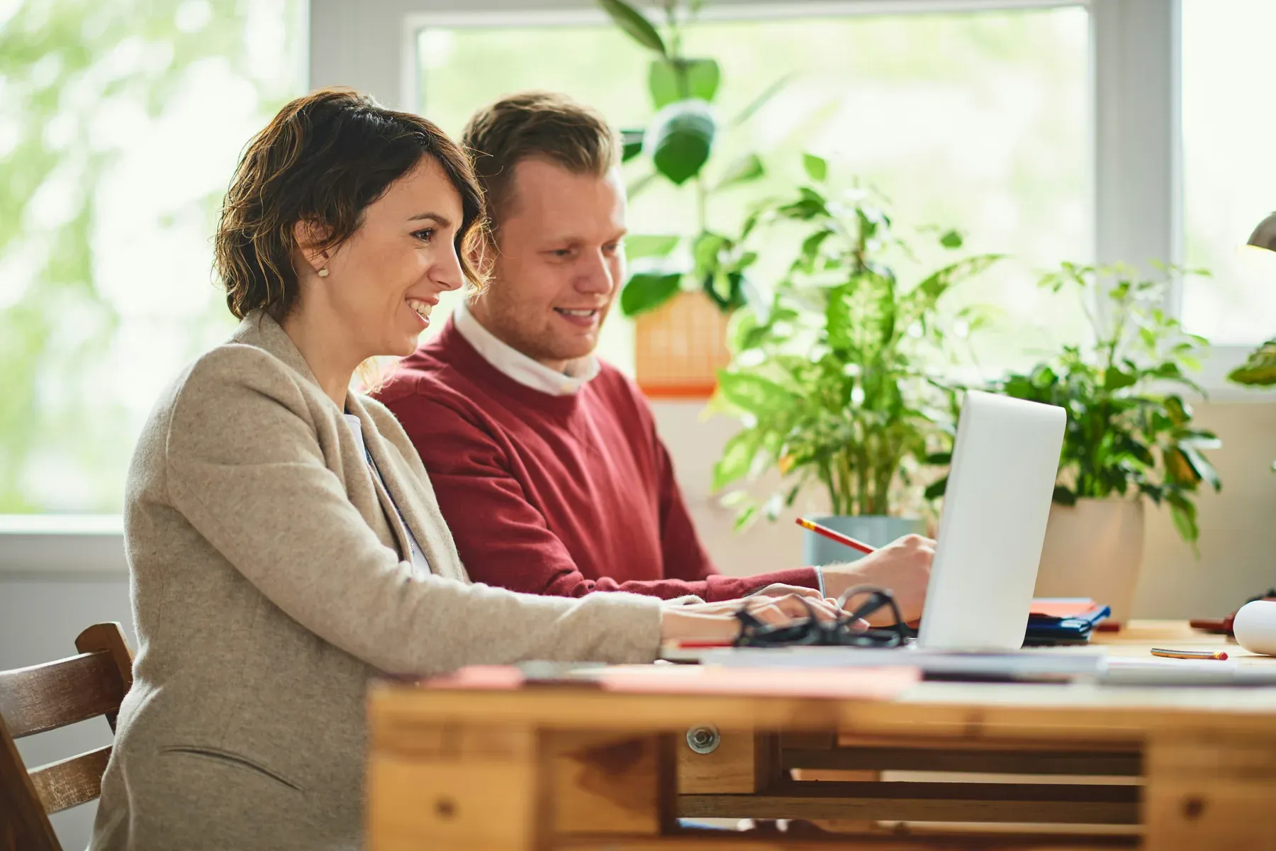 Two parents sitting at a table at home, looking at a laptop together
